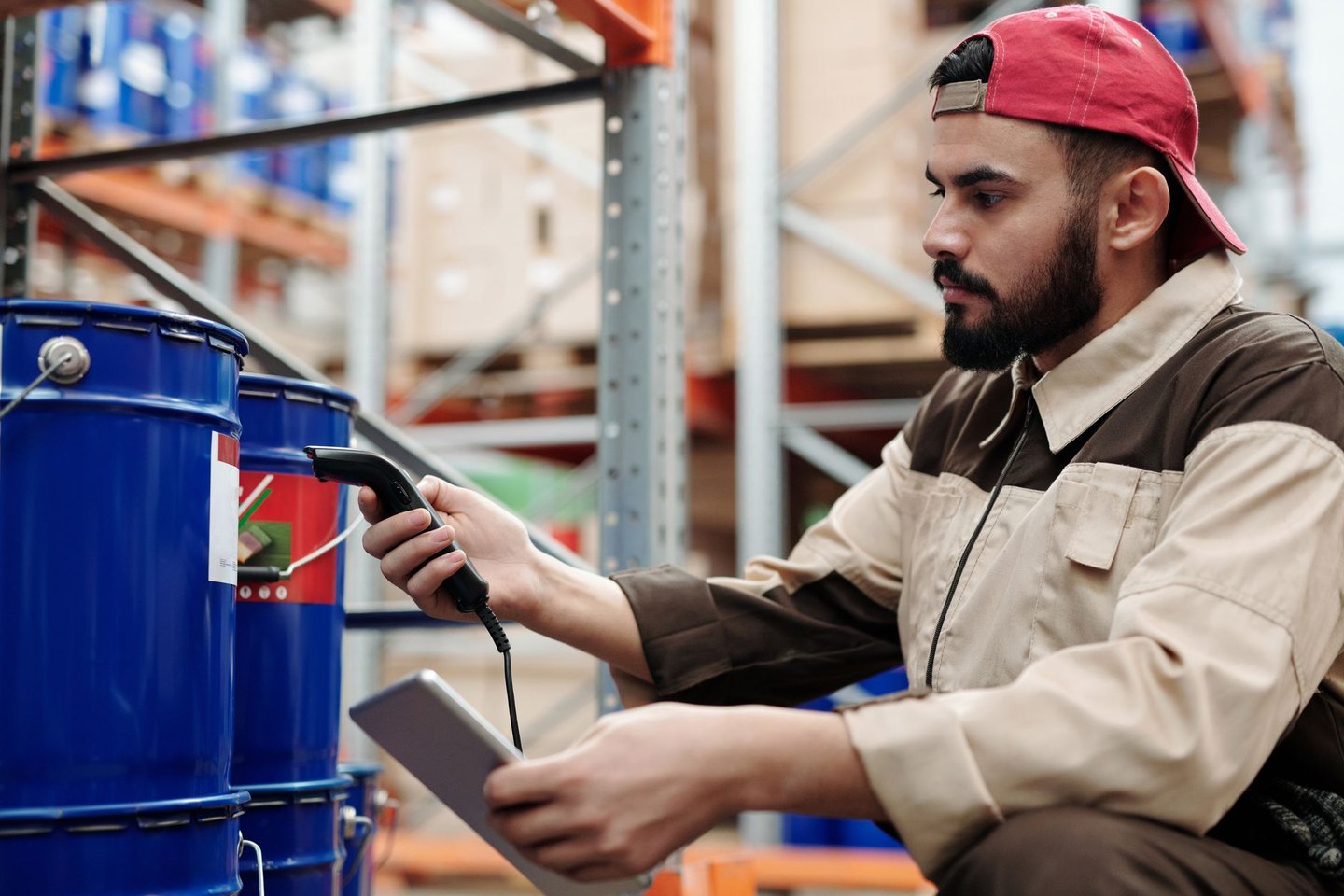 A depot worker crouched by stock with a handheld scanner and a tablet
